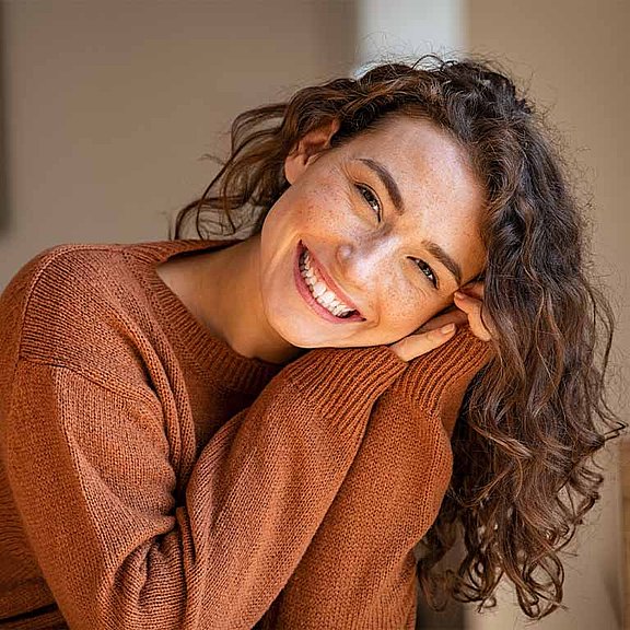 Wer einmal Lippenherpes hatte, hat mitunter mit wiederkehrenden Ausbrüchen zu kämpfen. Eine Frau lächelt in die Kamera.
