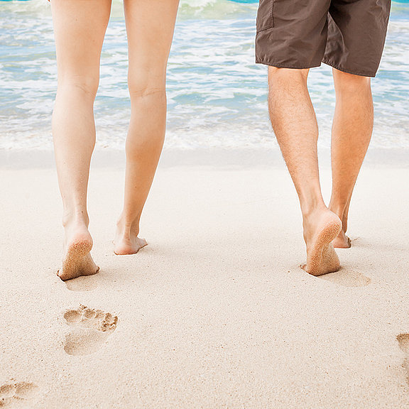 Zwei Menschen gehen am Strand spazieren