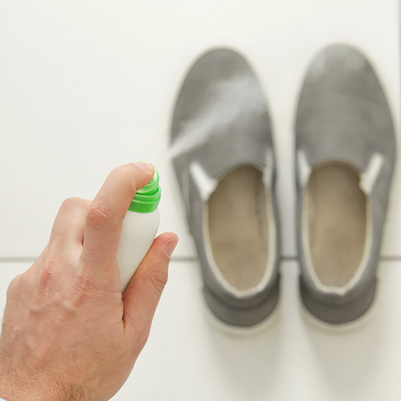Eine Person behandelt ihre Schuhe mit Desinfektionsspray.