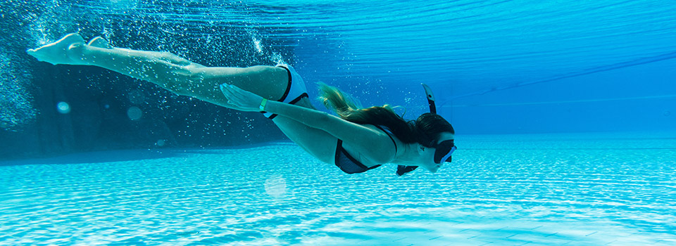 Unterwasseraufnahme von einer Frau, die in einem Pool taucht.